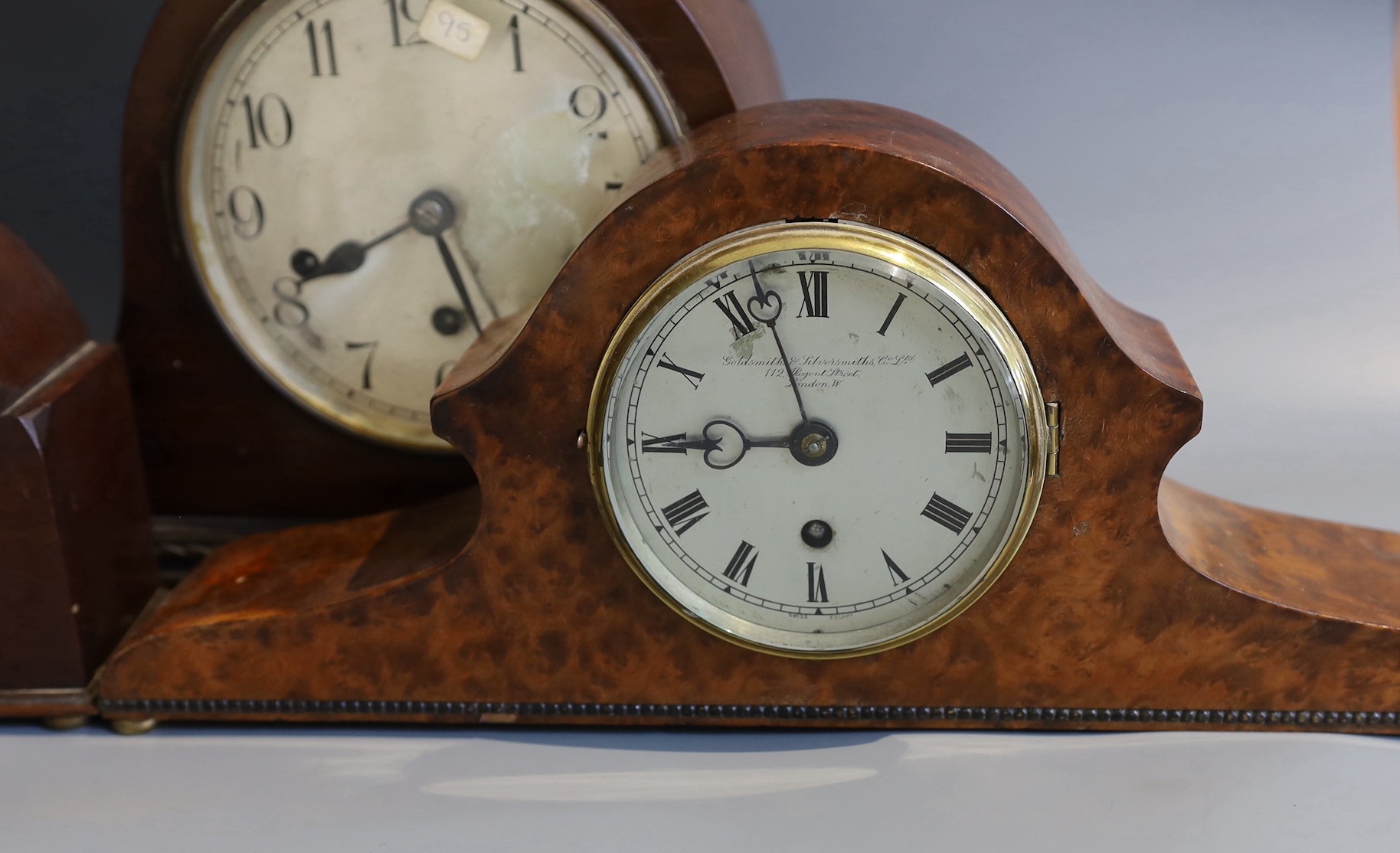 An early 20th century Goldsmiths & Silversmiths amboyna cased mantel clock, width 41cm, together with two other mantel clocks and a wall dial